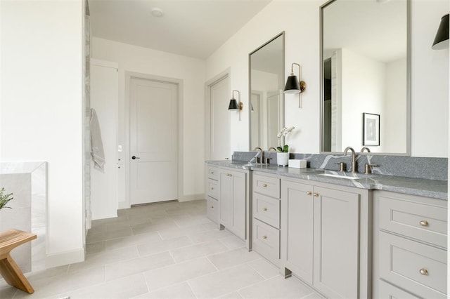 full bathroom featuring double vanity, tile patterned flooring, baseboards, and a sink