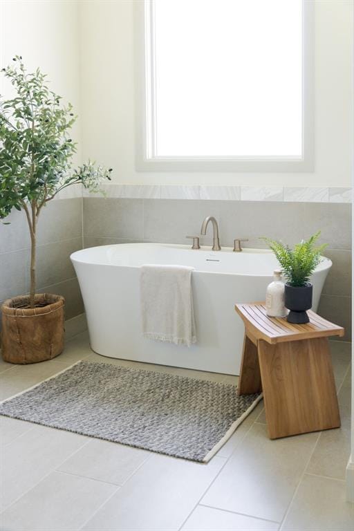 bathroom with tile walls, tile patterned floors, a wealth of natural light, and a freestanding bath