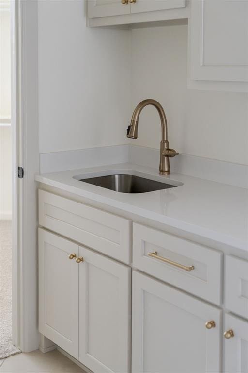 interior details featuring light countertops, a sink, and white cabinetry