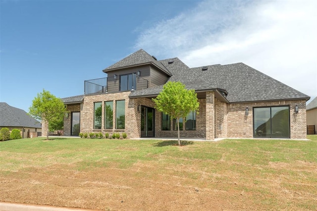back of property with a lawn, brick siding, roof with shingles, and a balcony