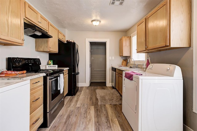 kitchen with light brown cabinetry, sink, light hardwood / wood-style flooring, appliances with stainless steel finishes, and washer / clothes dryer