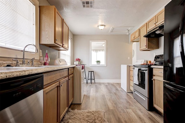 kitchen featuring sink, appliances with stainless steel finishes, light hardwood / wood-style floors, a textured ceiling, and light brown cabinetry