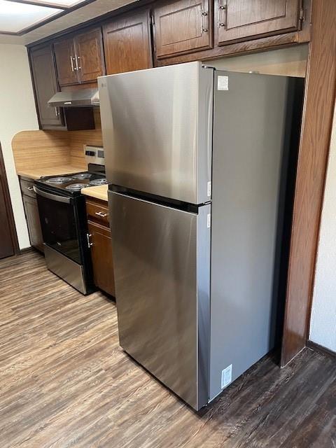 kitchen featuring appliances with stainless steel finishes, dark brown cabinets, and light wood-type flooring