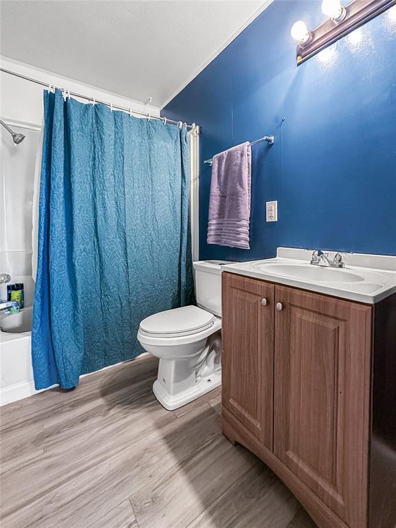 full bathroom featuring vanity, hardwood / wood-style floors, toilet, and shower / bath combo