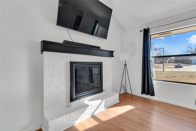 unfurnished living room featuring a brick fireplace and hardwood / wood-style floors