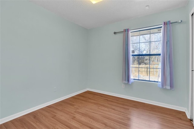 empty room with light hardwood / wood-style flooring and a textured ceiling