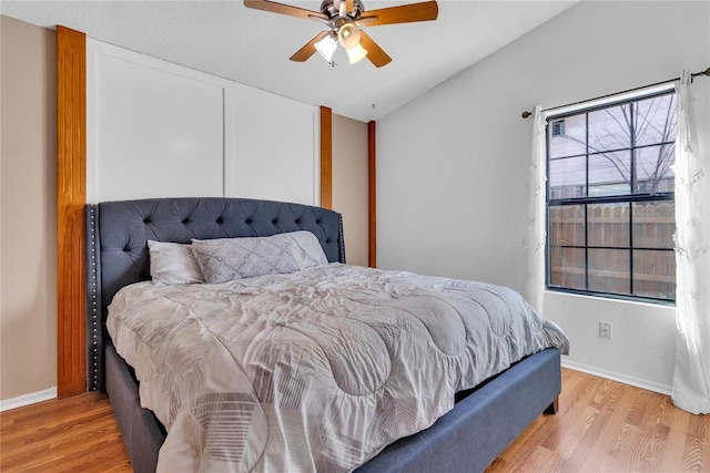 bedroom featuring light hardwood / wood-style flooring, ceiling fan, and vaulted ceiling