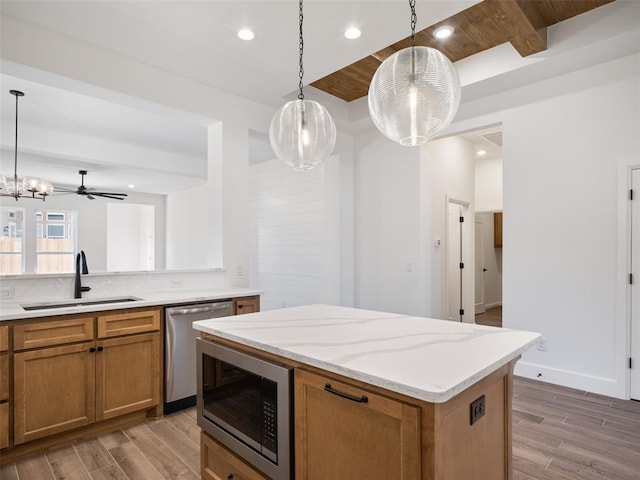 kitchen with sink, hanging light fixtures, built in microwave, stainless steel dishwasher, and light wood-type flooring