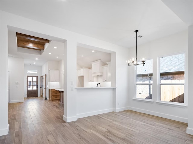 kitchen with light hardwood / wood-style flooring, white cabinetry, hanging light fixtures, a notable chandelier, and kitchen peninsula