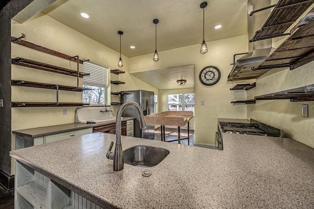 kitchen featuring pendant lighting, stainless steel fridge with ice dispenser, sink, and stove