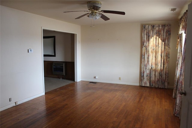 empty room featuring heating unit, dark hardwood / wood-style floors, and ceiling fan