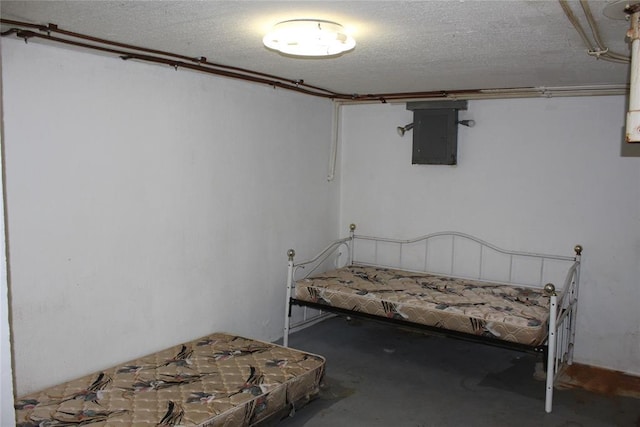 bedroom featuring electric panel, concrete floors, and a textured ceiling