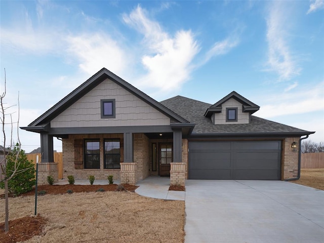 craftsman house with driveway, a garage, roof with shingles, covered porch, and brick siding