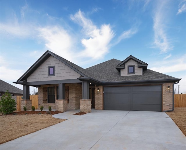 craftsman inspired home with a garage, concrete driveway, roof with shingles, fence, and brick siding