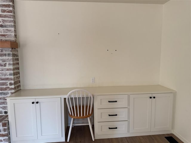 unfurnished office featuring dark wood-type flooring and built in desk