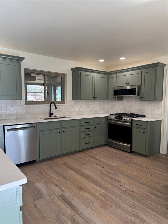 kitchen featuring green cabinetry, stainless steel appliances, sink, and wood-type flooring