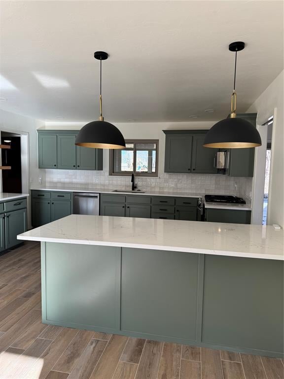 kitchen with pendant lighting, sink, stove, light stone countertops, and stainless steel dishwasher