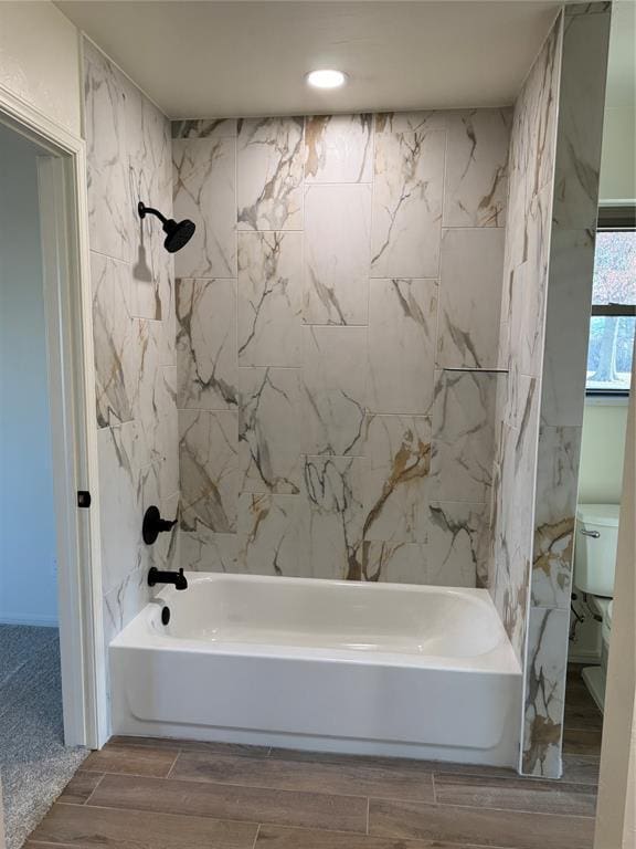 bathroom featuring tiled shower / bath and toilet