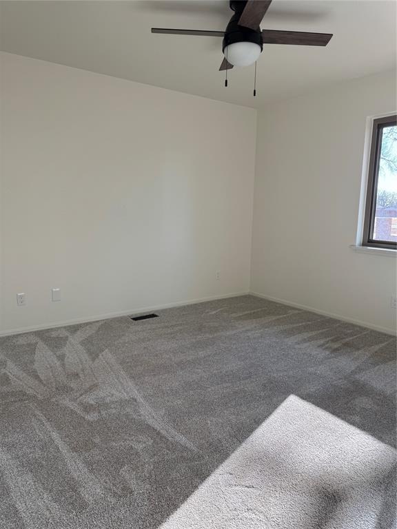 carpeted spare room with ceiling fan