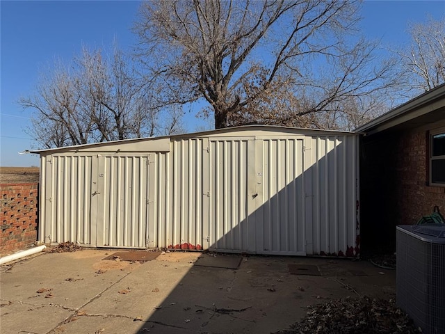 view of gate featuring a shed and central AC unit