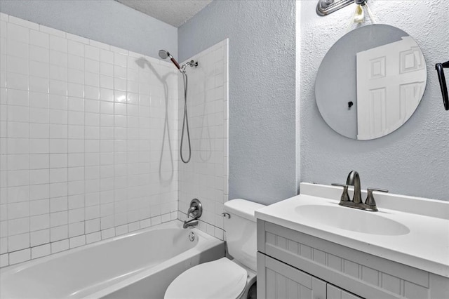 full bathroom featuring vanity, tiled shower / bath combo, toilet, and a textured ceiling