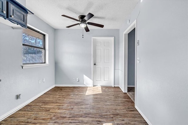 spare room featuring ceiling fan, dark wood-type flooring, and a textured ceiling