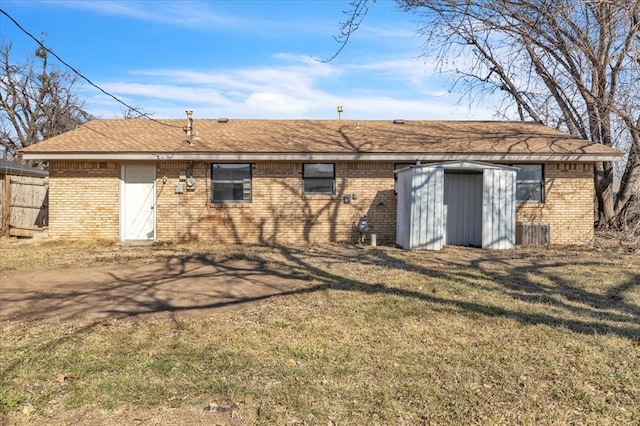 back of house with a storage unit and a lawn