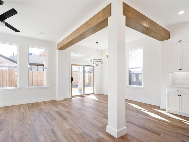 unfurnished living room with beamed ceiling, a healthy amount of sunlight, and light hardwood / wood-style flooring