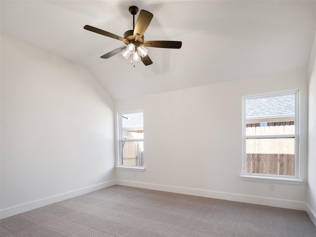 spare room with ceiling fan, plenty of natural light, vaulted ceiling, and light carpet