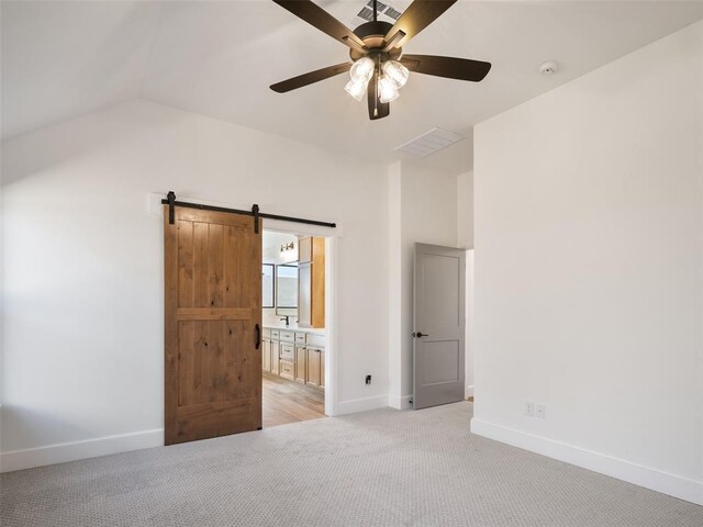 carpeted spare room featuring ceiling fan, a barn door, and vaulted ceiling