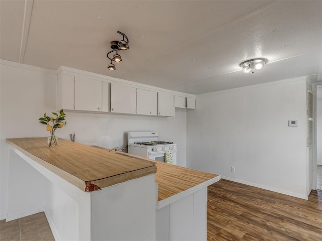 kitchen with dark hardwood / wood-style flooring, kitchen peninsula, white range with gas stovetop, and white cabinets