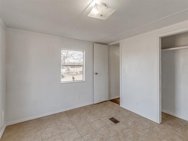 unfurnished bedroom featuring crown molding, light tile patterned flooring, and a closet