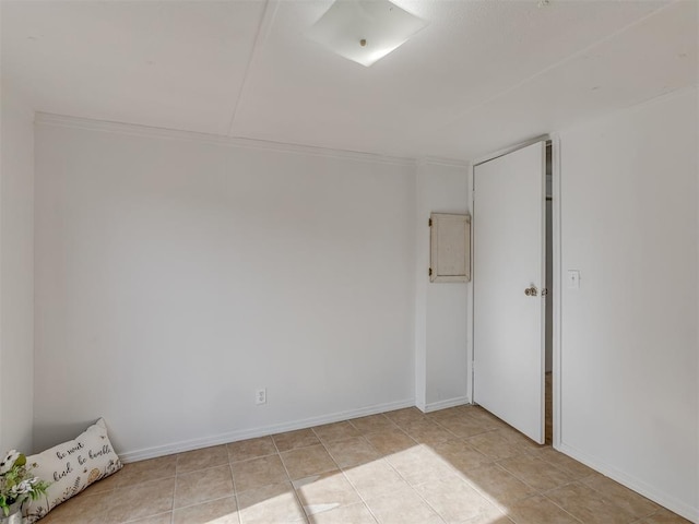 empty room featuring light tile patterned flooring and baseboards