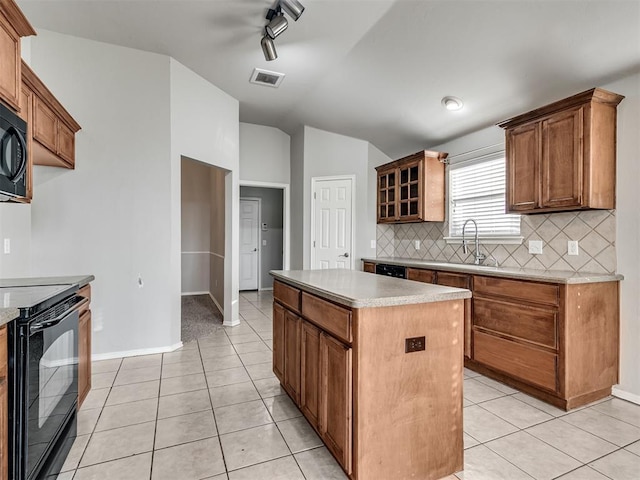 kitchen featuring vaulted ceiling, light tile patterned flooring, backsplash, a center island, and black appliances