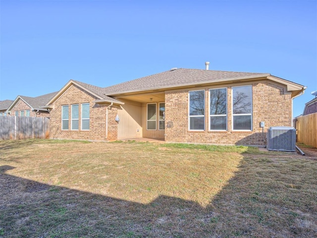 rear view of property with a yard and central air condition unit