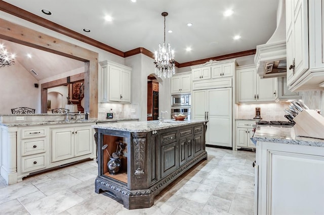 kitchen featuring built in appliances, custom range hood, pendant lighting, and a center island