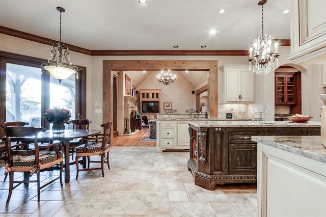 kitchen with ornamental molding, light stone countertops, an inviting chandelier, and decorative light fixtures