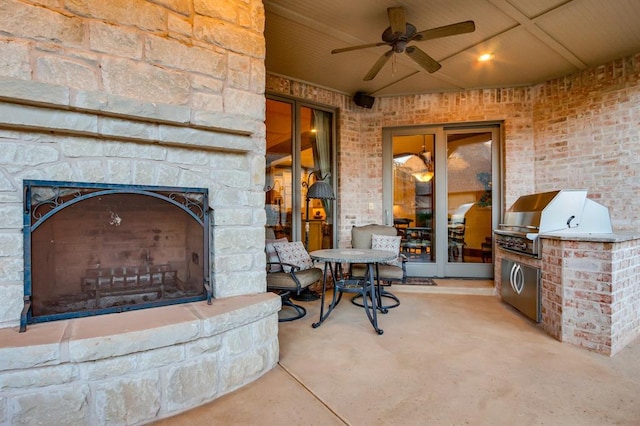 view of patio with ceiling fan, area for grilling, and an outdoor stone fireplace