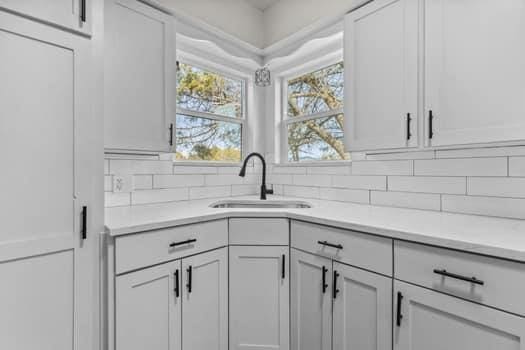 kitchen featuring tasteful backsplash, sink, and white cabinets