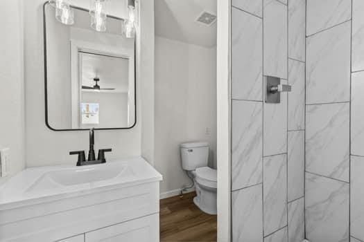 bathroom featuring vanity, hardwood / wood-style floors, toilet, and a tile shower