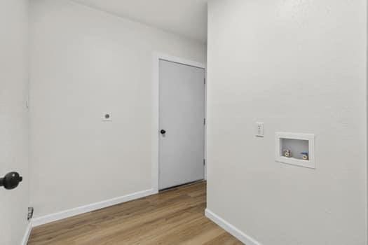 clothes washing area with hookup for an electric dryer, washer hookup, and light hardwood / wood-style flooring