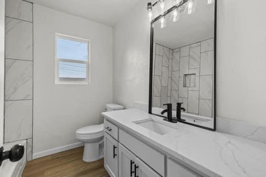 bathroom with wood-type flooring, toilet, and vanity