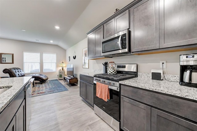 kitchen with lofted ceiling, dark brown cabinetry, light stone counters, stainless steel appliances, and light hardwood / wood-style floors