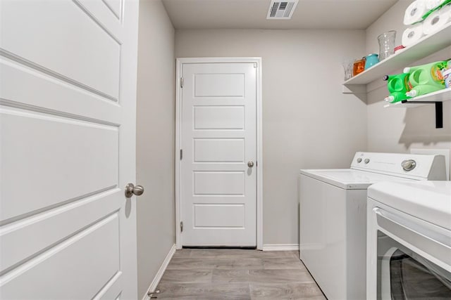 laundry area with washing machine and dryer and light hardwood / wood-style flooring