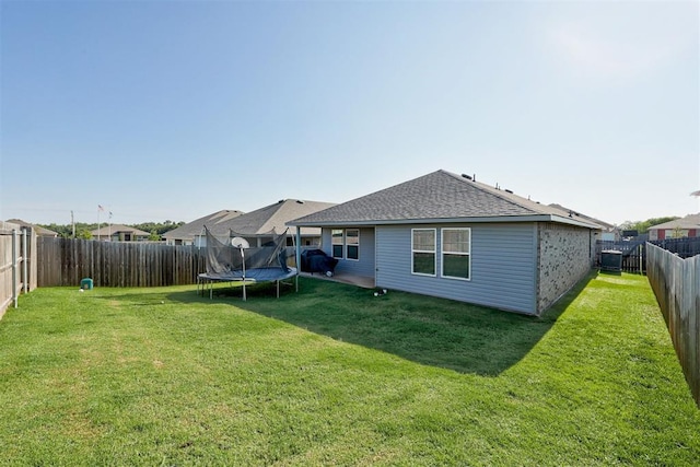 back of property featuring a trampoline and a lawn