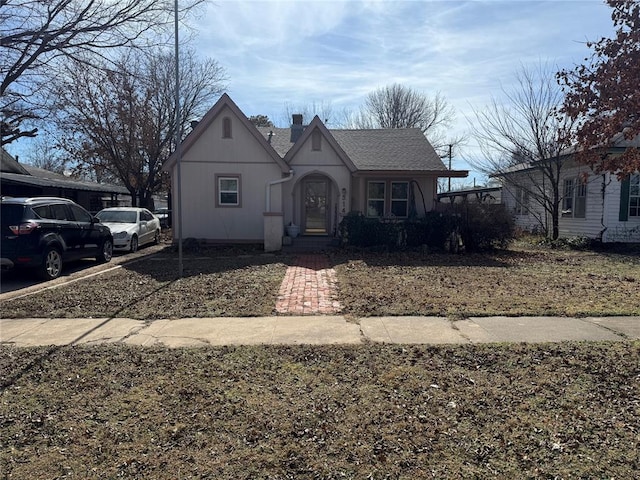 view of front of home with a chimney and roof with shingles