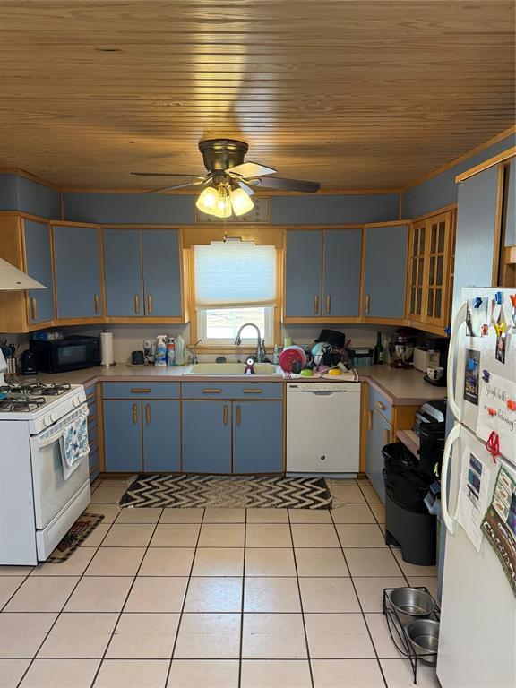 kitchen featuring light tile patterned floors, wooden ceiling, white appliances, a sink, and light countertops