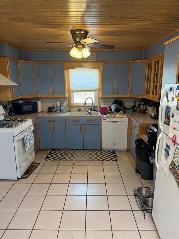 kitchen with white appliances, wood ceiling, light countertops, a sink, and light tile patterned flooring