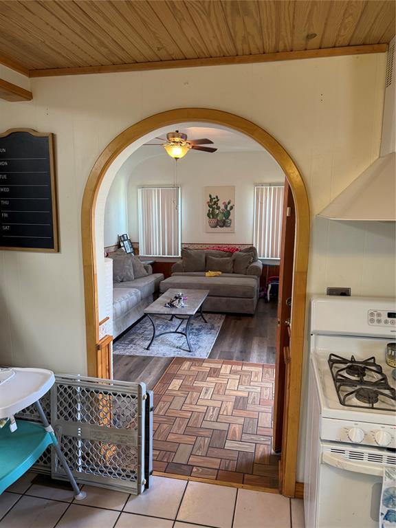 tiled living room featuring arched walkways, ceiling fan, and wood ceiling