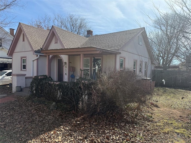 view of front facade with roof with shingles and a chimney